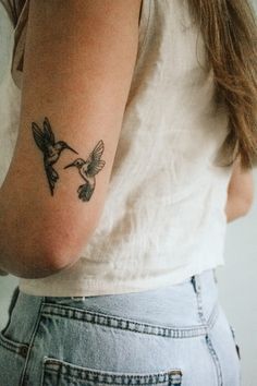 a woman with a hummingbird tattoo on her left arm and right arm behind her back