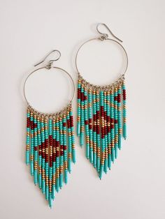 Introducing our Zuri Beaded Earrings. Crafted with hypoallergenic stainless steel posts, these earrings are gold dipped and hand beaded with turquoise, maroon and golden beads. The unique design makes them light on the ears. Add a touch of elegance to any outfit with these expertly crafted earrings. Hoop Earrings Indian, Indigenous Beaded Earrings, Bead Jewelry Patterns, Wire Jewerly, Crafted Earrings, Diy Fashion Ideas, Seed Bead Jewelry Patterns, Beadwork Ideas, Earring Inspo