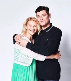 a man and woman hugging each other in front of a white background with a green pleated skirt