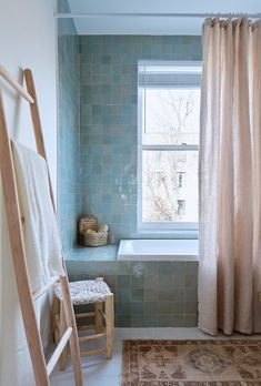 a bathroom with a bathtub, rug and ladder in it's corner next to a window