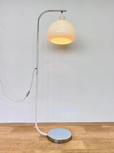 a floor lamp that is on top of a wooden floor next to a white wall