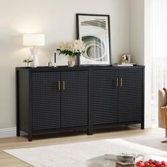 a black sideboard with gold handles in a living room next to a white rug