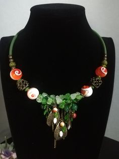 Beautiful handmade choker necklace with vintage swirl Marble&Glass stones, jade, mother of pearl and glass beads. Anyone who chooses this necklace will inevitably be captivated by the beautiful swirl beads in bright orange. The necklace has a hanging part of cascading bronze and green leaves. The necklace is rigid, sits perfectly on the neck and has an adjustable hook closure with a 5 cm extension. The necklace is very showy and elegant, it recalls autumn, nature... Suitable for a low-cut dress, for those who love to be extravagant. The necklace can also be purchased in a kit with earrings. All jewels are delivered in a decorated box, ready to be given as a gift to your loved one. How to take care of your jewellery: put on your beauty products (cosmetics, perfumes, ...) before wearing your Bohemian Beaded Jade Necklaces, Bohemian Jade Beaded Necklaces, Bohemian Beaded Jade Necklace, Bohemian Jade Pendant Necklace, Unique Adjustable Decorative Necklaces, Adjustable Jade Jewelry With Colorful Beads, Bohemian Handmade Glass Necklaces, Adjustable Colorful Beaded Jade Jewelry, Vintage Green Jewelry With Unique Variations