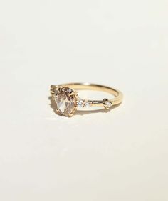 a yellow gold ring with an oval stone and two small diamonds on the band, set in