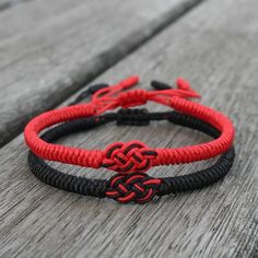 two red and black bracelets sitting on top of a wooden table