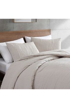 a bed with white sheets and pillows on top of it