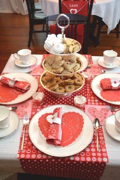 a table set for valentine's day with heart shaped cookies