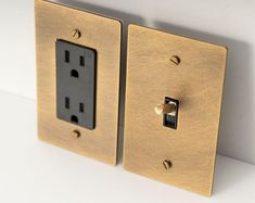 an electrical outlet on the wall with two switches and one light switch in gold plated metal