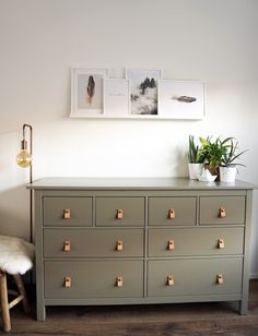 a dresser with several drawers and pictures on the wall