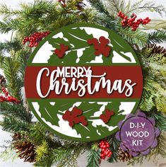 a christmas wreath with the words merry christmas in red and green on it, surrounded by pine