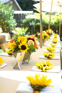 the tables are set with sunflowers in vases and napkins on them