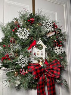 a wreath on the front door with a birdhouse and snowflakes hanging from it