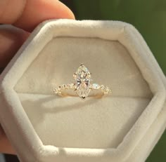 a person holding an engagement ring in their hand with the diamond set on it's side