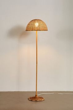 a floor lamp with a bamboo shade on it's base and a cord plugged in