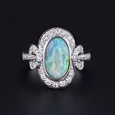 Opal and Diamond Ring: Experience the timeless beauty of this semi-black opal elegantly encased in 18k white gold and adorned with sparkling diamonds. The face of the 1990s ring measures 0.75 inches by 0.5 inches wide, and it is in great condition.  The ring is a size 6.5, but it can be resized free of charge. Your ring will arrive elegantly packaged, ready for gifting or as a special treat for yourself. Each piece is carefully wrapped to ensure a delightful unboxing experience. We also offer fr Formal Opal Ring With Polished Finish, Formal Multi-stone Opal Ring With Diamonds, Formal Multi-stone Diamond Opal Ring, Formal Fine Jewelry Opal Ring With Brilliant Cut, Luxury Diamond Opal Ring For Formal Occasions, Luxury Opal Gemstone Ring For Formal Occasions, Formal White Gold Opal Ring With Brilliant Cut, Luxury Sterling Silver Oval Opal Ring, Classic Multi-stone Opal Ring For Formal Occasions