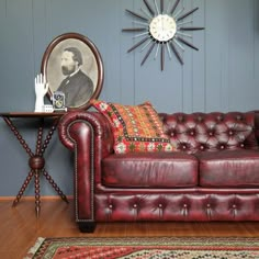 a red leather couch sitting on top of a hard wood floor next to a table