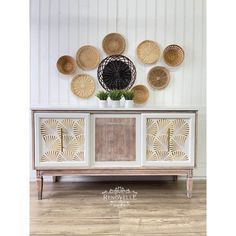 a white and gold sideboard with wicker baskets on it's back wall