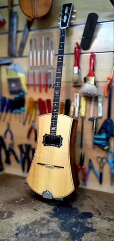 a guitar sitting on top of a table in a room filled with lots of tools