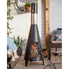 a fire pit sitting on top of a patio next to a chair and potted plant