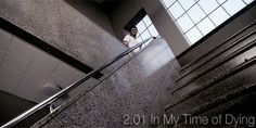 a woman standing on the top of an escalator next to a window in a building