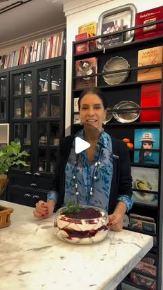 a woman standing in front of a counter holding a plate with food on top of it