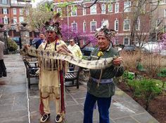 two men dressed in native american garb holding a snake