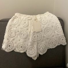 a white crochet doily sitting on top of a gray couch next to a wall