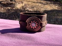 Brown Leather Cuff with a copper round tribal design and a double snap closure The band is 1-3/4" wide. It will fit a wrist measuring 6-1/2". It is made with a medium weight leather. Please check measurements for proper fit. This cuff can be made in a different size if needed. ' Leather Cuffs, Brown Leather, Cuff Bracelets, Copper, Jewelry Bracelets, Cuff, Band, Leather, Design