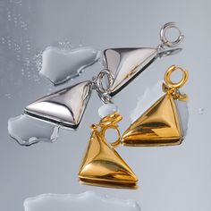 Meet your new statement piece: the Vanguard Gold Earrings. These sleek, geometric beauties are designed to turn heads and elevate your style game. Crafted with a high-shine 18 karat gold finish, these earrings feature a bold triangular design that dangles elegantly, creating a modern and sophisticated look. The unique pyramid shape of the earrings adds an edgy flair, making them perfect for both casual and formal outfits. Notice how they catch the light beautifully, highlighting the clean lines Elegant Triangle Metal Earrings, Modern Triangle Gold Hoop Earrings, Modern Triangle Earrings For Party, Modern Triangle Party Earrings, Modern Single Triangle Earring, Modern Triangle Metal Earrings, Black Friday Jewelry, Jewelry Organizer Storage, Natural Stone Bracelets