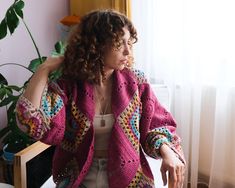 a woman sitting at a table in front of a window with her hand on her head