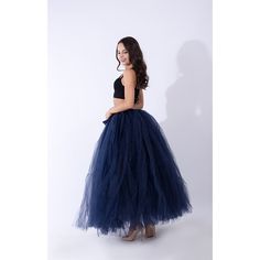 a woman in a black top and blue tulle skirt standing against a white background