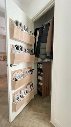 an open closet with shoes on shelves and clothes hanging from the wall in front of it