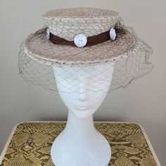 Brand: College Miss Hats  Size: 23 (see measurements) Color: ecru/brown/cream  Fabric Content: straw/tulle/ plastic    Features: You couldn't help but have a good time in this hat. Monochromatic color scheme with a chocolate brown grosgrain ribbon hat band, ecru hat and white buttons around the band. Sweet and fun. The netting is in great condition.    Measurements: Crown Circumference: 18in  Height: 2in  Brim:2 ½ in Strap Length:   Condition: Very good vintage condition. This hat was decommissioned from a museum's collection and has been well-preserved.   Care: spot clean only  Vintage sizing varies. Please check your measurements thoroughly and ask any questions before your purchase. No returns or exchanges. Condition is noted in the product description and can be observed using the zoom Fitted Retro Cream Hat, Vintage Beige Visor Hat, Retro Fitted Cream Hat, Retro Cream Hat, Retro Beige Short Brim Hat, Retro Cream Hat With Curved Brim, Vintage Beige Top Hat With Curved Brim, Vintage Beige Top Hat With Short Brim, Fitted Cream Brimmed Sun Hat