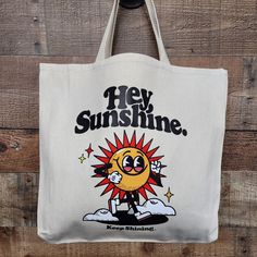 a white tote bag with an image of a cartoon sun on the front and words hey sunshine