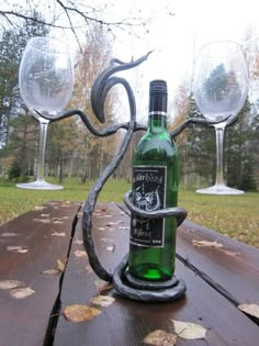 a wine bottle holder with two wine glasses on top of it, sitting on a picnic table