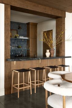 a bar with stools and counter tops in a room that has wood paneling on the walls