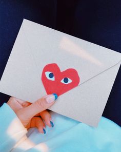 a person holding an envelope with a red heart cut out of it's side