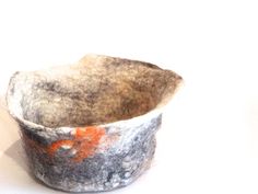 a bowl made out of felt with orange and white paint on the inside, sitting on a white surface