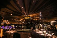 the inside of a tent with tables and chairs set up for a wedding reception at night