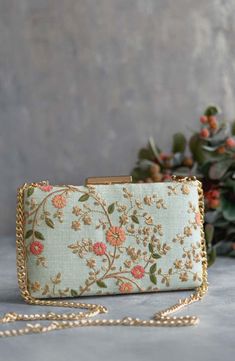 Our Floral creeper clutches are super-hot, year-round! The traditional silhouette with exquisite floral embroidery and the metal chain sling are perfect to add that oomph to your overall look and make a strong style statement, no matter what the occasion. Embroidered front and back. Dimensions (LxB): 8"x4.5" (20 cm x 11 cm) Handle length: 47" (120 cm) Handle drop: 23" (58 cm) Material: Embroidered poly silk, poly satin lining, gold metal clutch frame, gold metal sling. Features: metal lock closu Bridal Boxes, Strong Style, Floral Handbags, Embroidered Clutch, Silk Bag, Floral Purse, Potli Bags, Diwali Gifts, Box Clutch