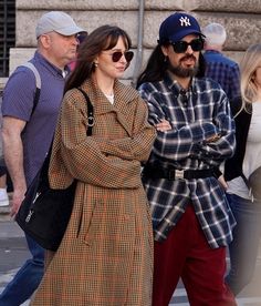 two people are walking down the street with their arms crossed and one is wearing sunglasses