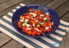 a blue bowl filled with tomatoes and feta cheese