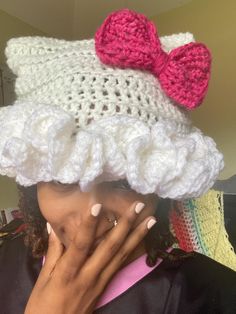 a woman wearing a crocheted hat with a pink bow