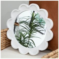 a round mirror sitting on top of a table next to a brown pillow and basket