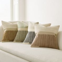 four pillows sitting on top of a white couch