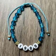 the necklace has three beads with numbers on it and is attached to a blue cord