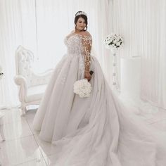 a woman in a white wedding dress standing next to a chair with flowers on it