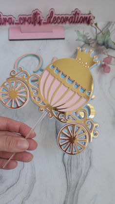 a pink and gold baby carriage with a crown on it's head is being held by a person