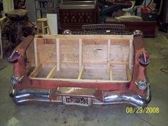 the back end of an old car with wood in it's trunk and seat