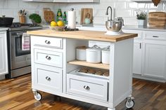 a kitchen with white cabinets and wood flooring, including an island in the middle